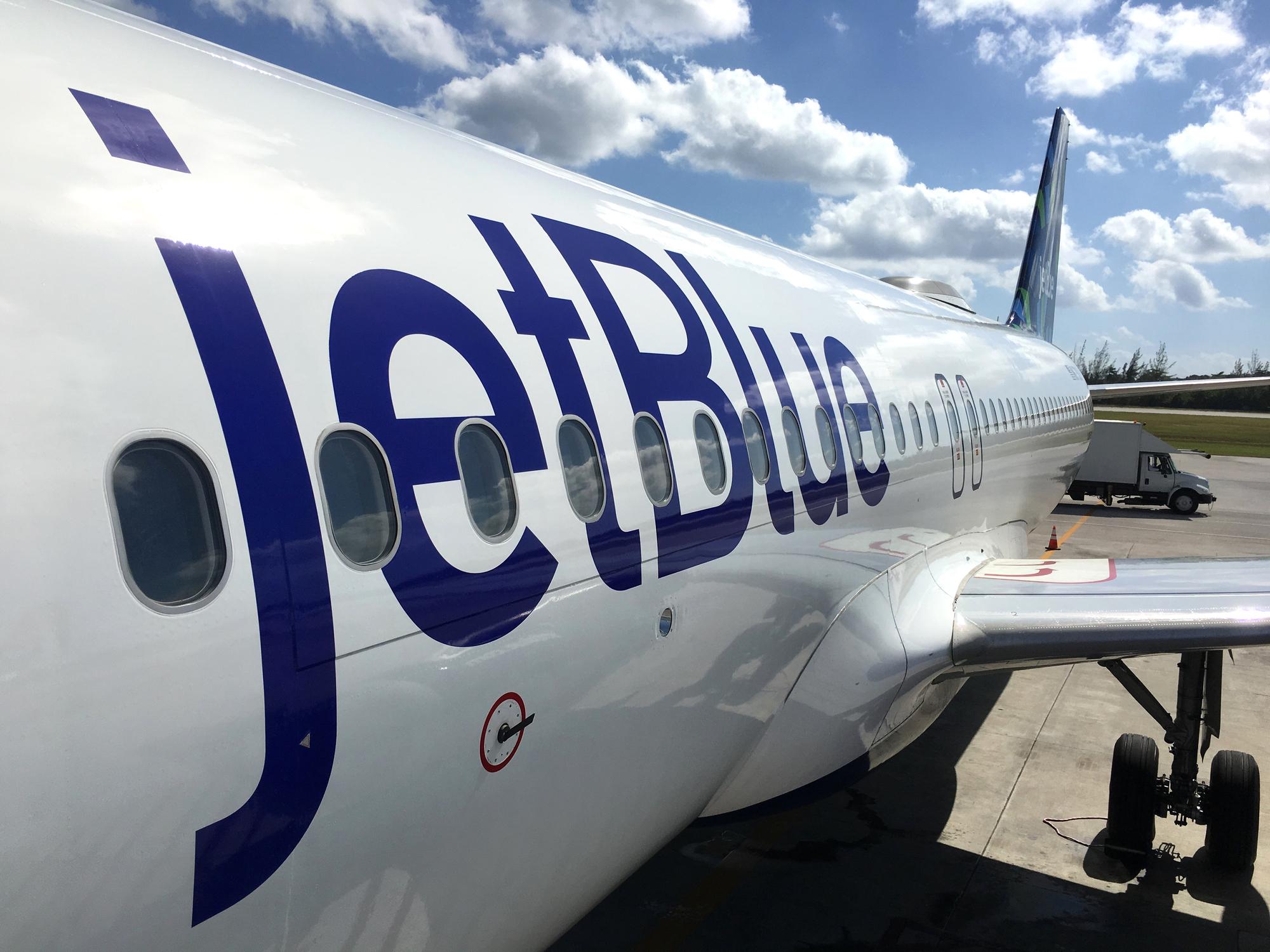 Land operations and boarding in Owen Roberts Intl. Airport in Grand Cayman Islands. Close up of a JetBlue plane in a sunny day.