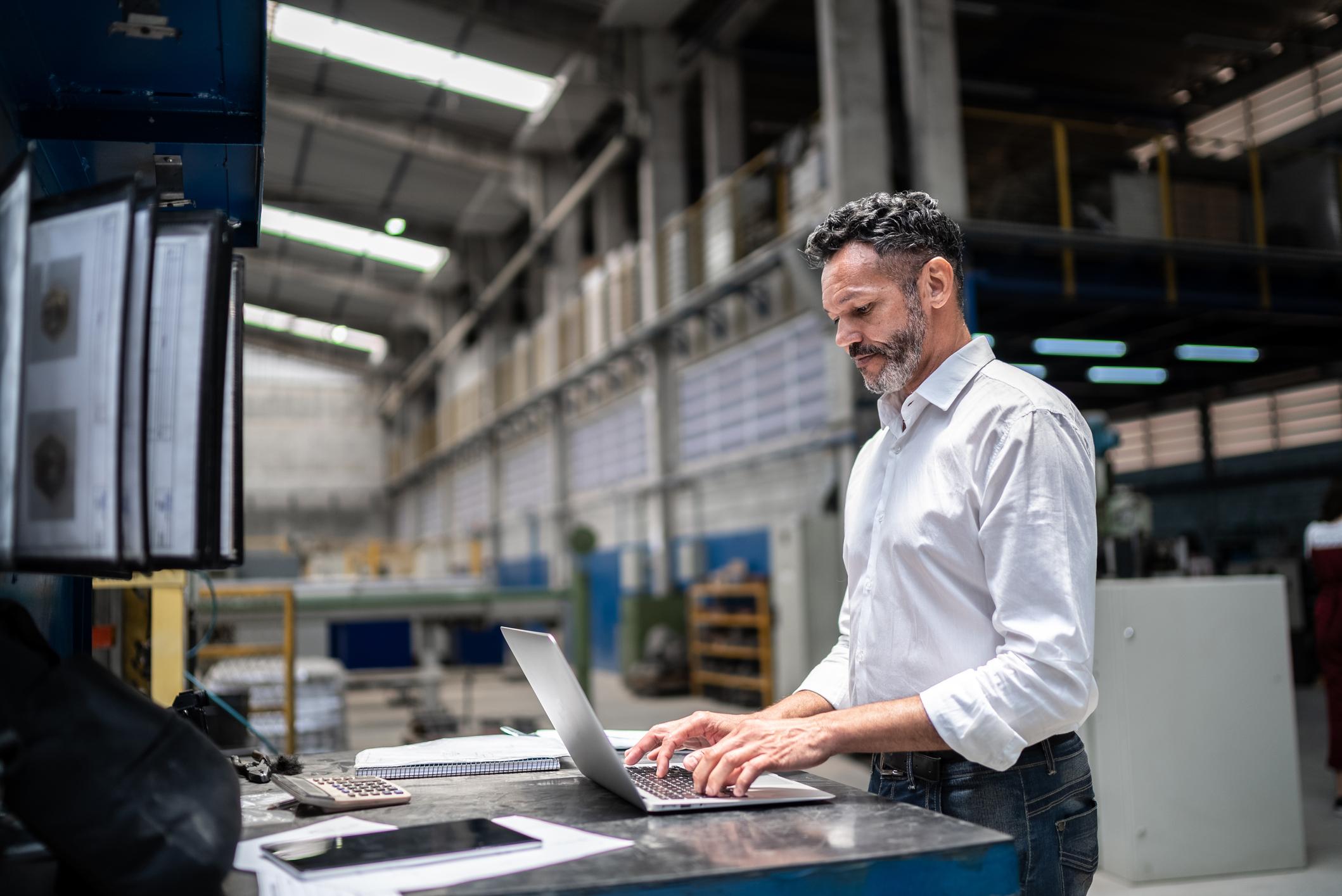Businessman using laptop in a factory