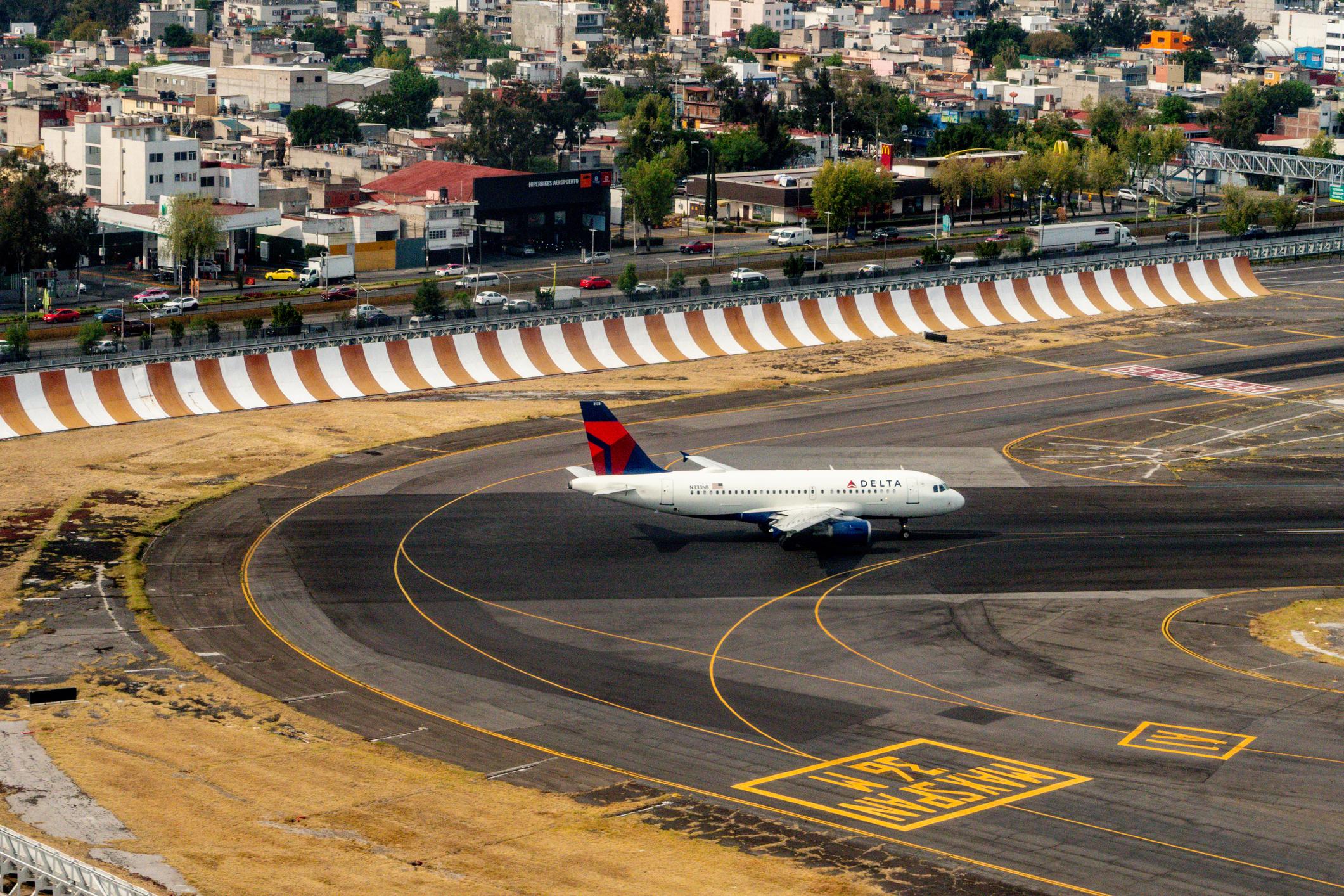 Delta Air Lines Airbus A319 (N333NB) starts its takeoff roll at Mexico City International Airport (MEX), with dense residential neighborhoods visible