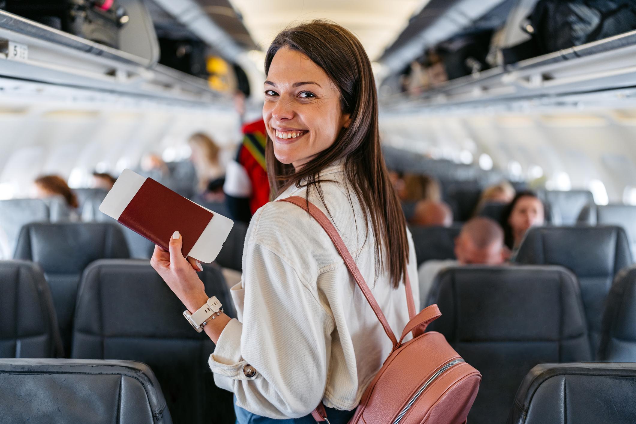 Portrait of a young woman boarding an airplane in Austria. Finding her seat.