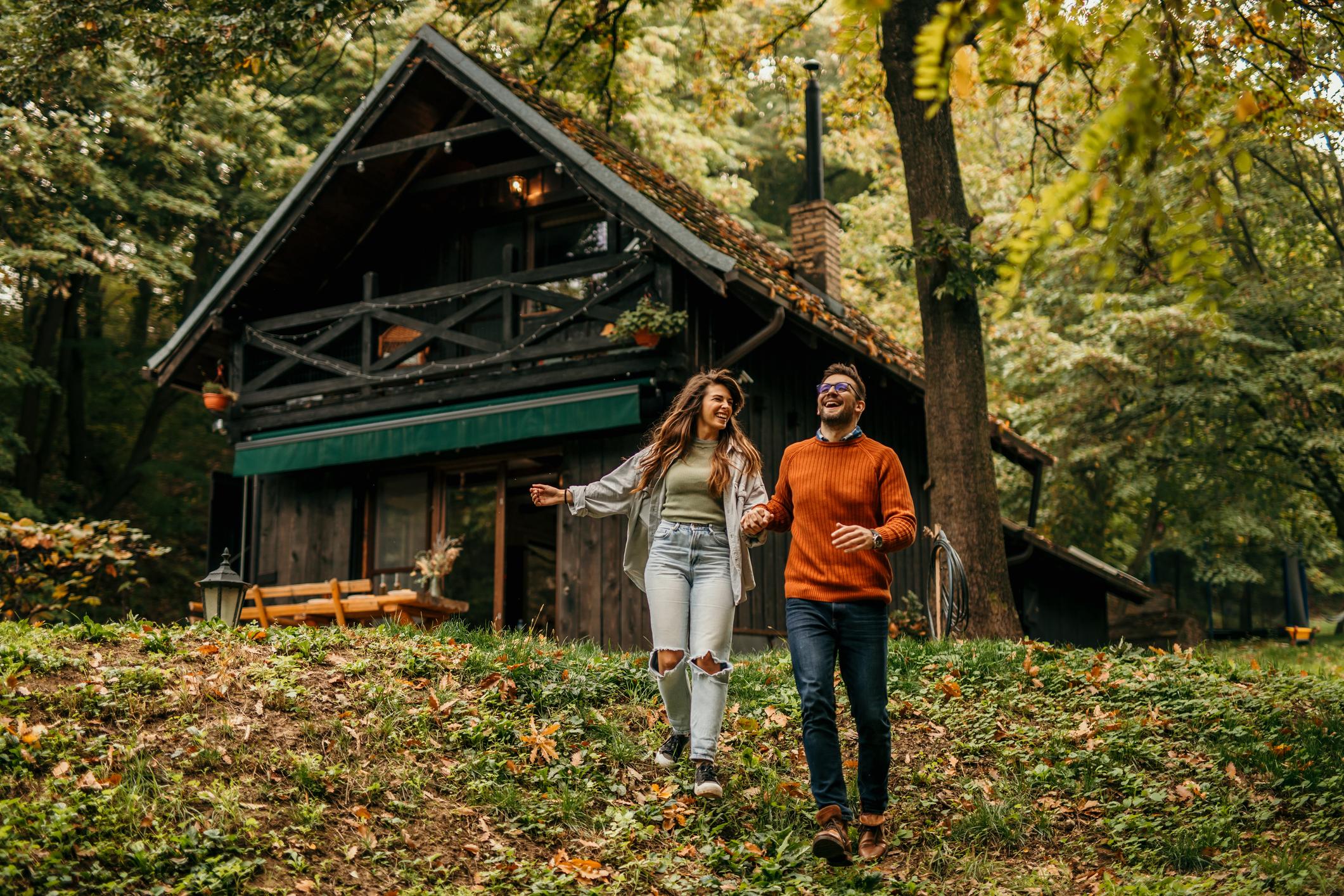 Loving couple holding hands and enjoying running downhill at the rented vacation house