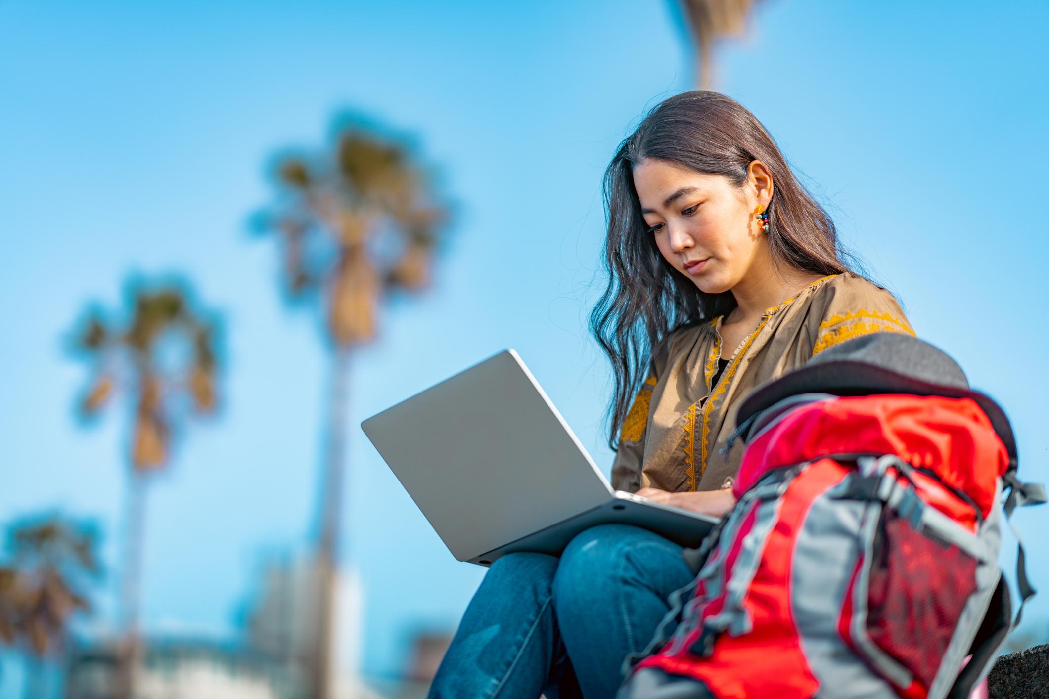 A young female traveller is using her laptop on her vacation.