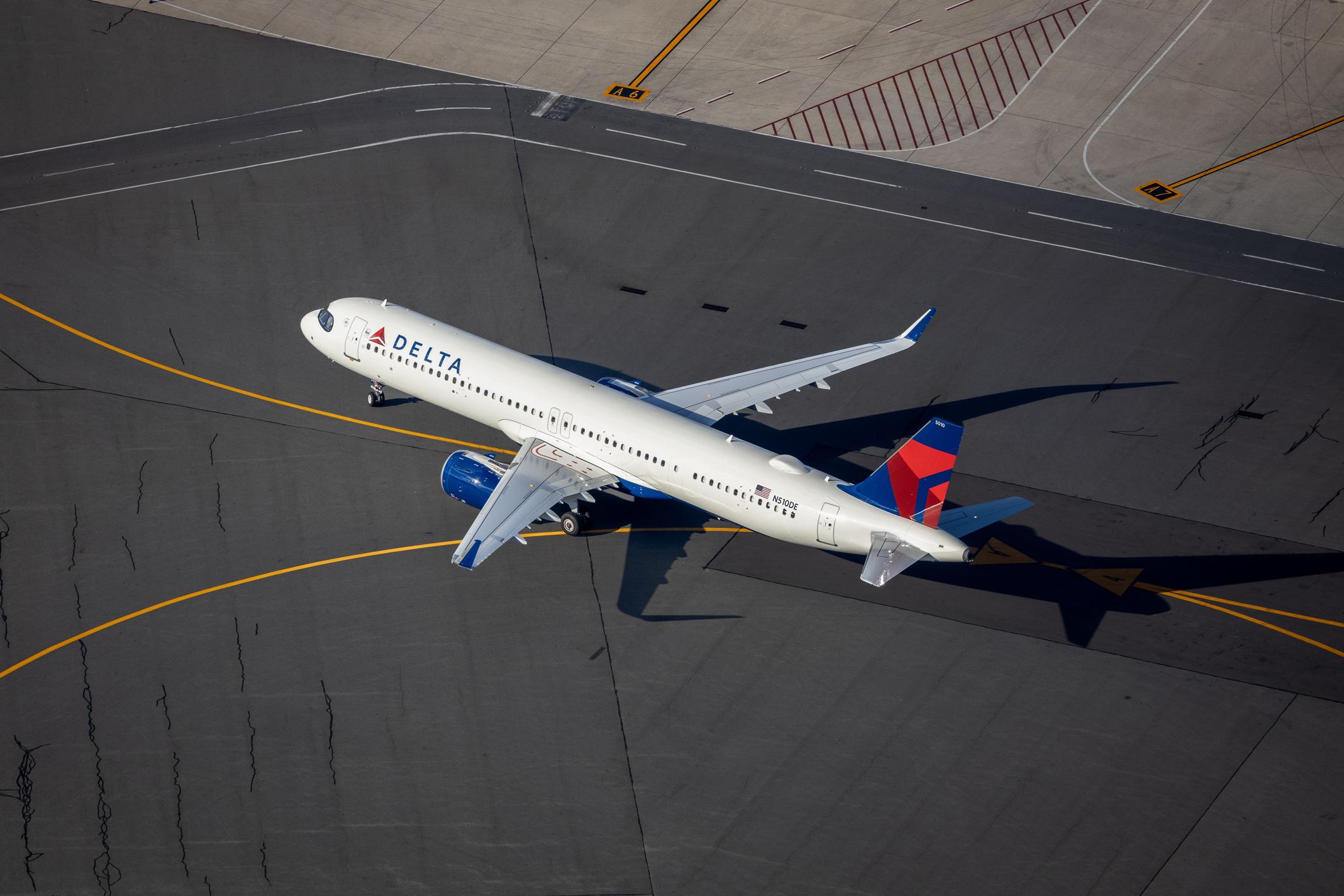 An aerial shot of a Delta Airlines plane taxiing at an airport in Boston.