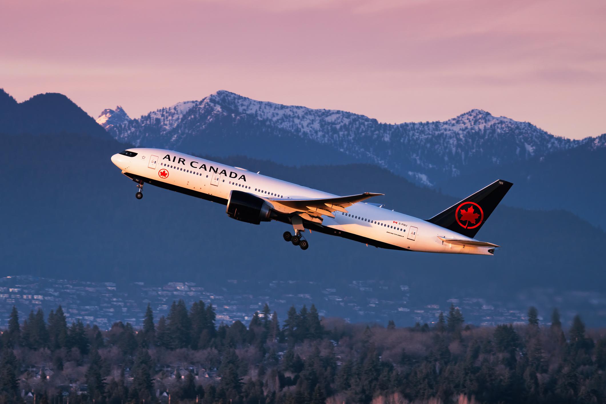 Air Canada Boeing 777 taking off from Vancouver International Airport during sunset.
