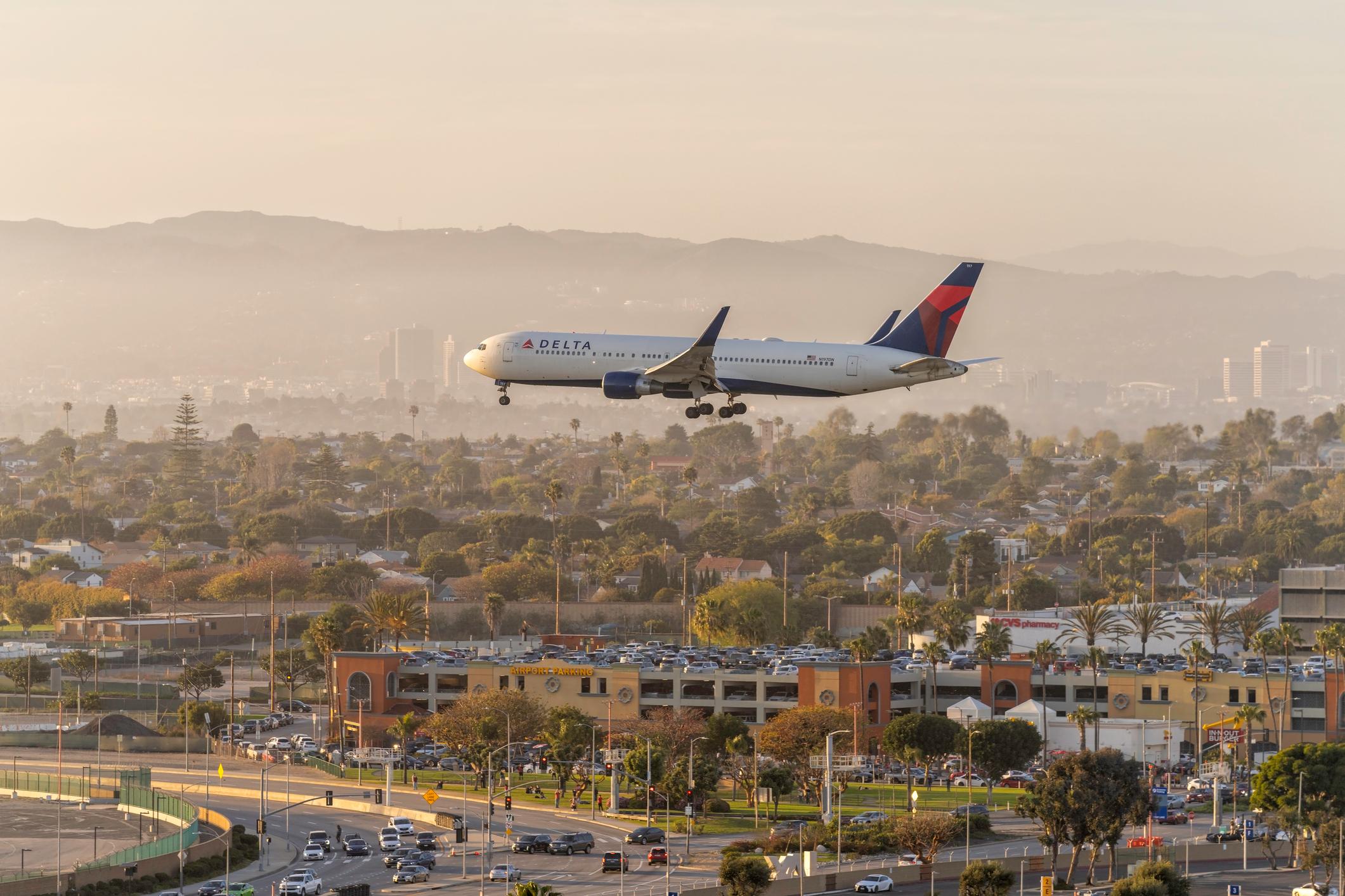 Delta Airlines airplane on landing approach to LAX Airport in Los Angeles. City buildings in the background